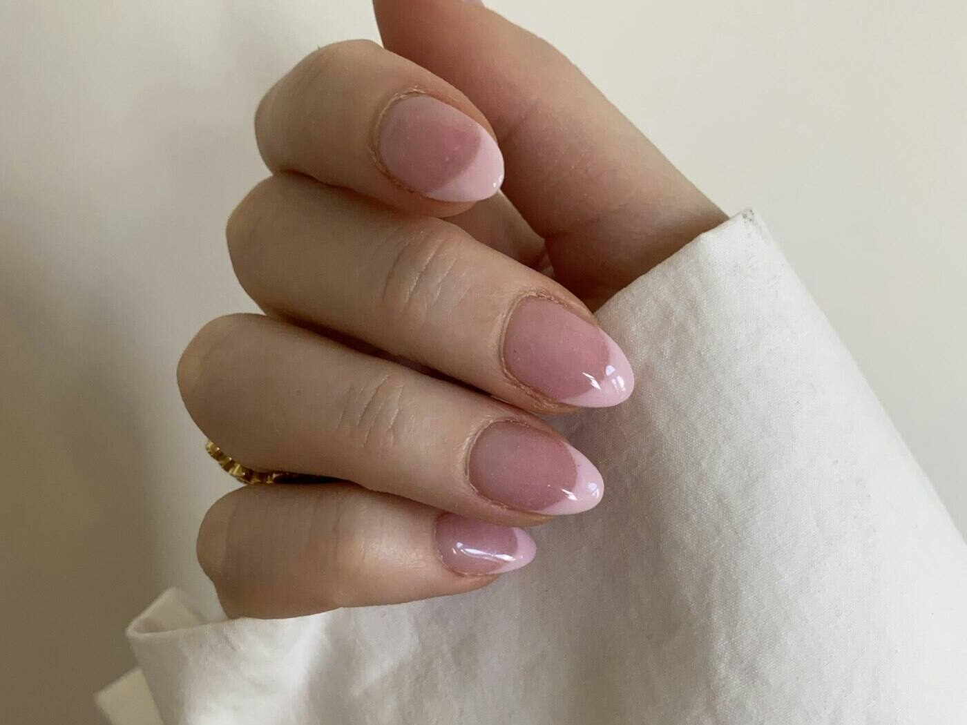 Hand with a soft pink manicure resting on white linen